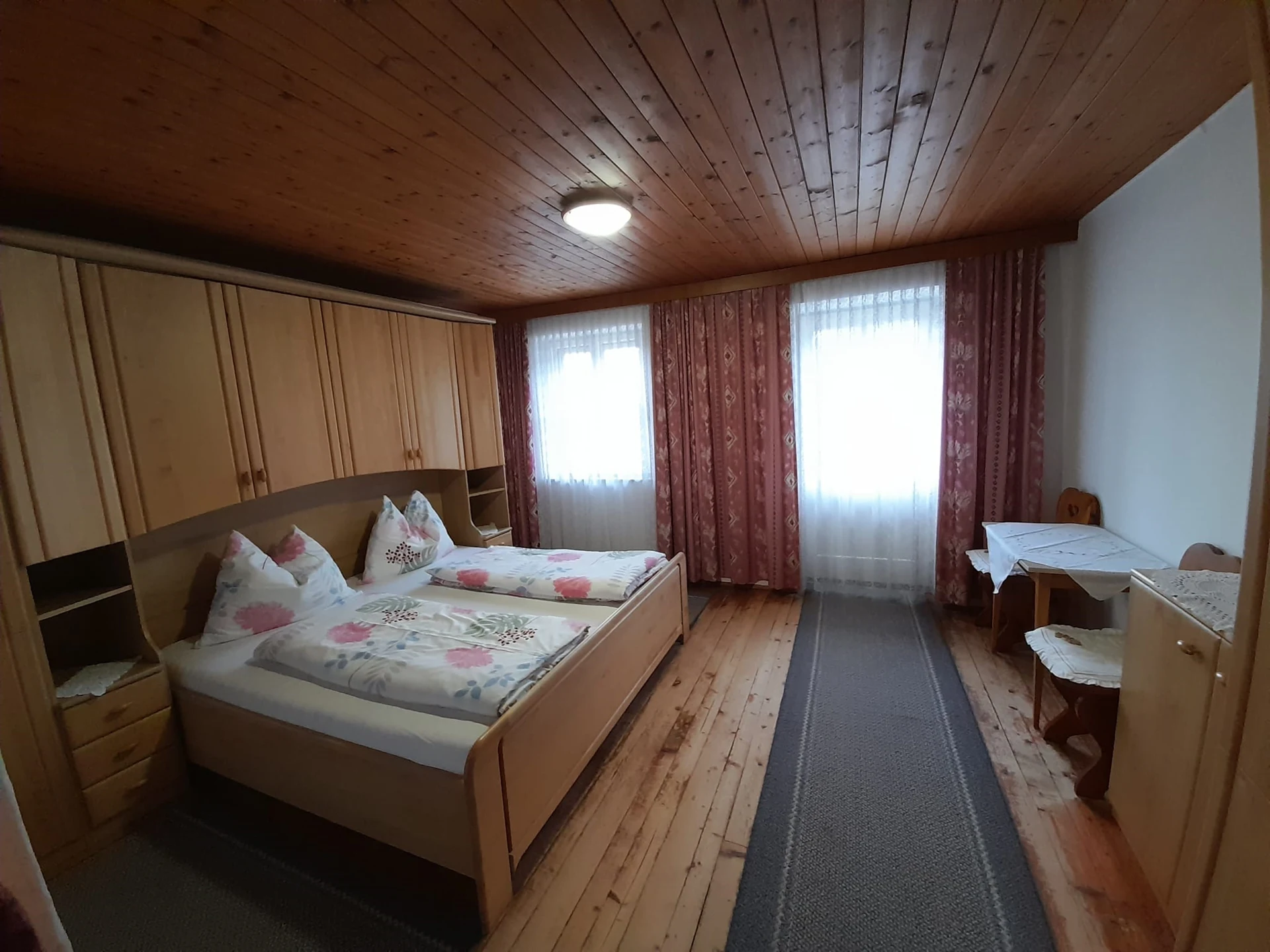 Doppelzimmer mit Holzfußboden und zwei großen Fenstern